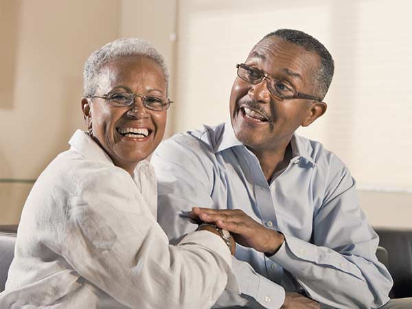 Mature African-American couple, wearing glasses and sitting on the sofa